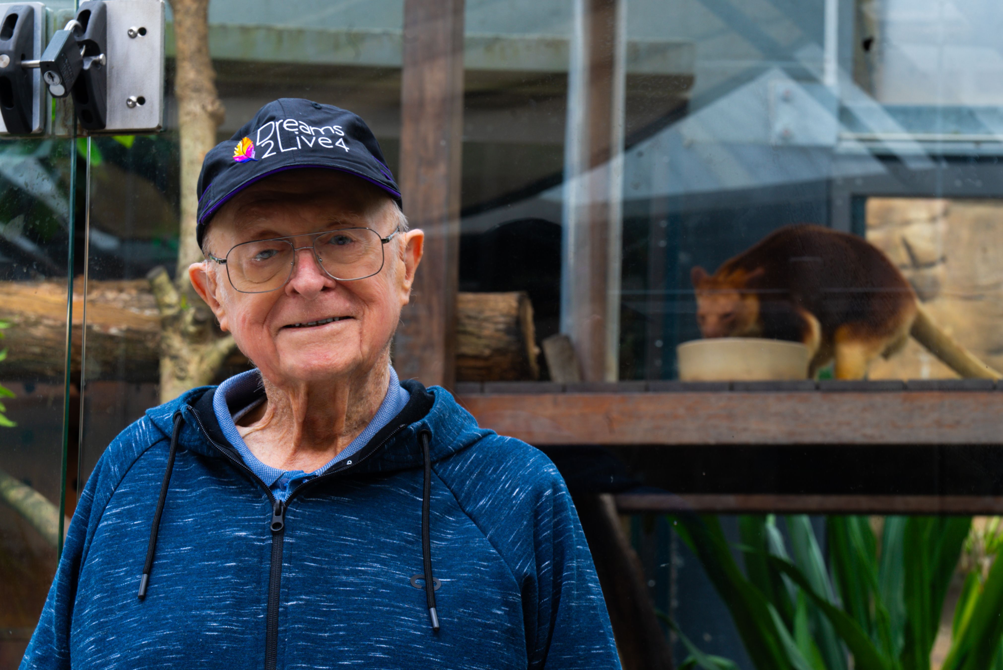 Elderly man with Dreams2Live4 hat with tree kangaroo in background.